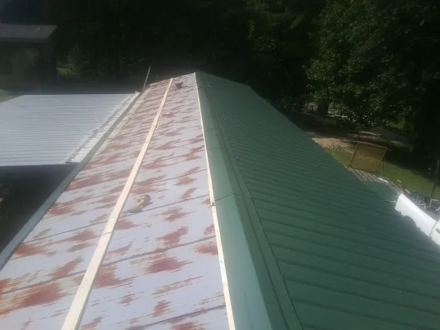 Old rusted panels beside newly installed green metal roofing — Wind Damage Roof Repair by Roofing Brothers in Council Bluffs