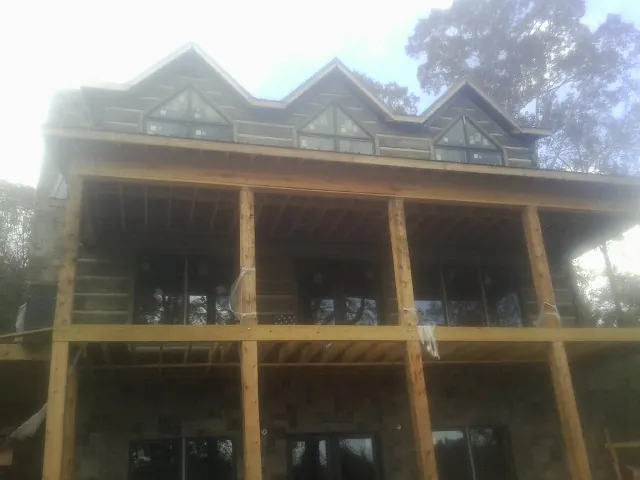 Dormers and porch framing on a large log home under construction — Roof Coating work by our crew in Council Bluffs