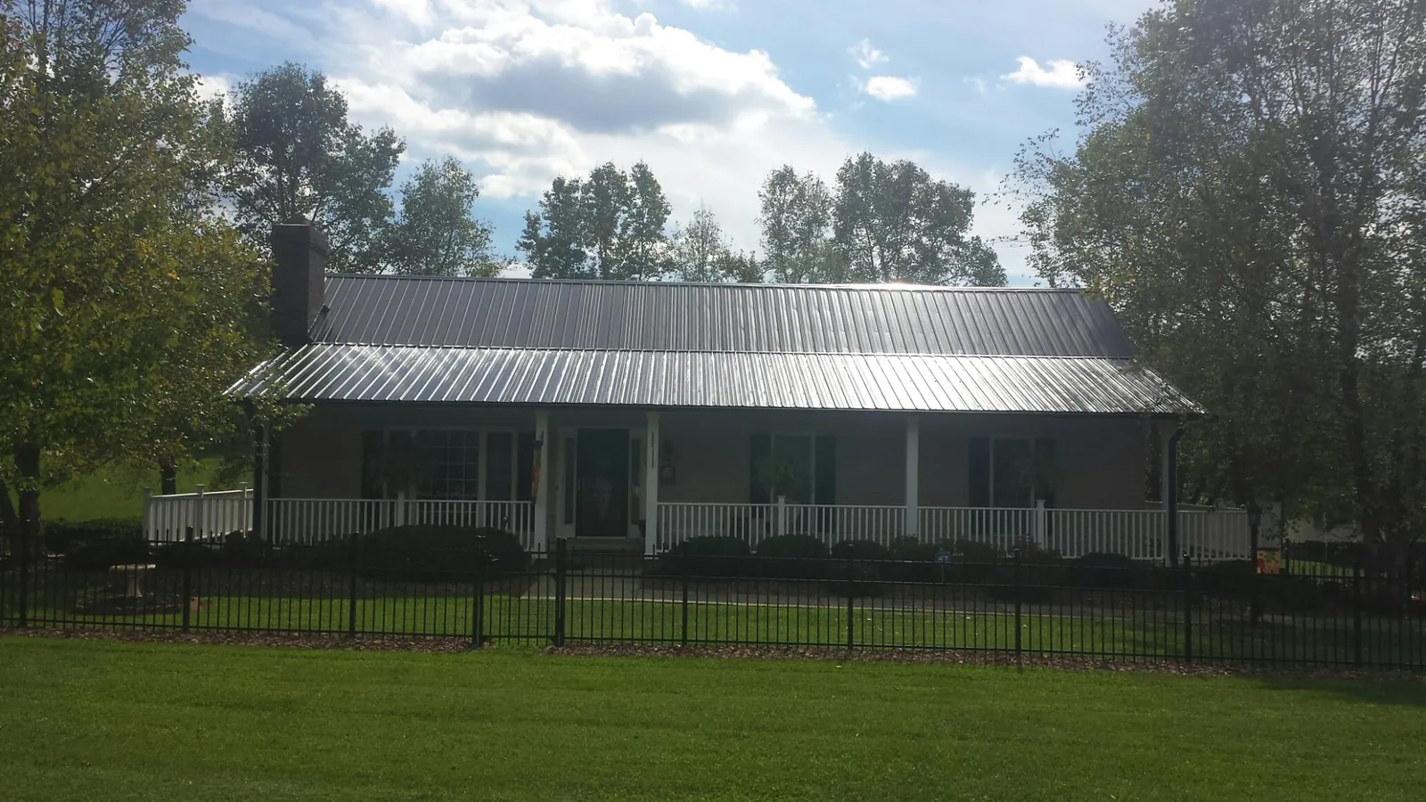 Gray metal roof on a brick ranch with a full width front porch — Gutter Guard Installation work by our crew in Council Bluffs