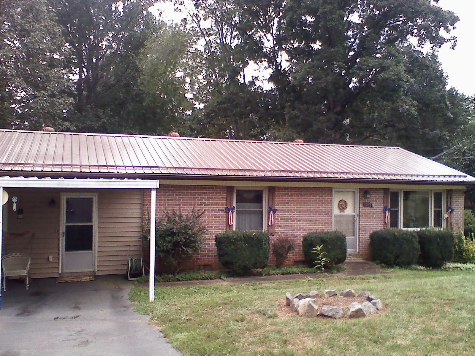 Bronze metal roof and carport on a brick ranch home — Roof Repair work by our crew in Council Bluffs