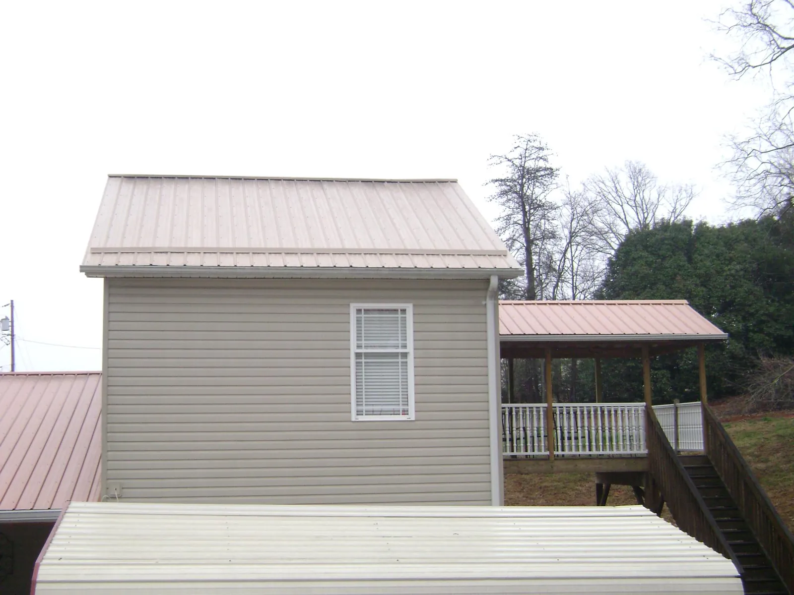 Tan metal roofs on a two story addition and attached porch, from a Roof Replacement job in Council Bluffs