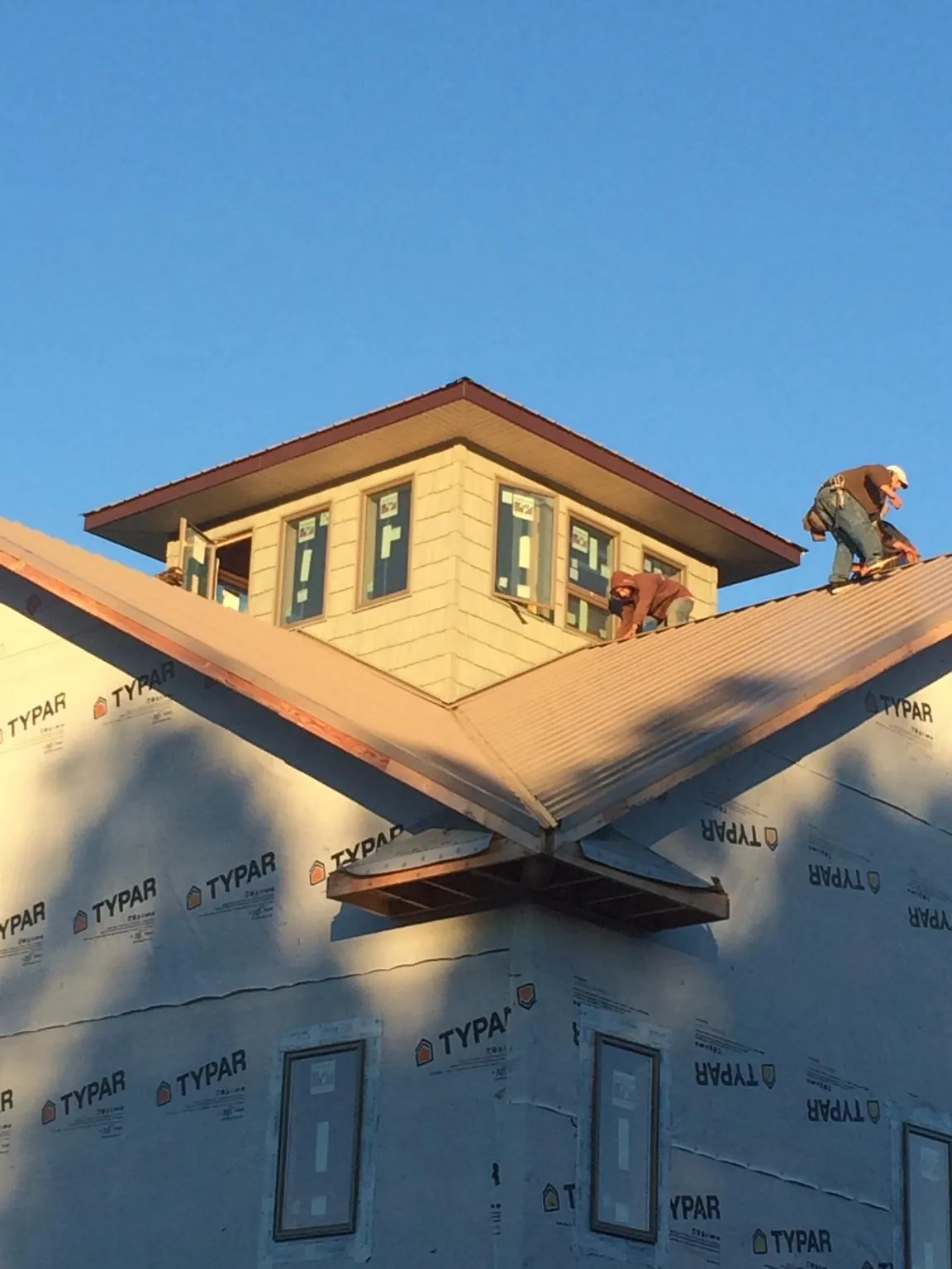 Roofers working around a rooftop cupola on a new metal roof at sunset — Roof Waterproofing in Council Bluffs by Roofing Brothers